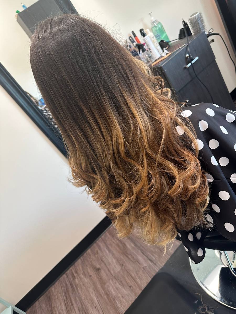 Warm caramel balayage worn in loose, glossy waves
