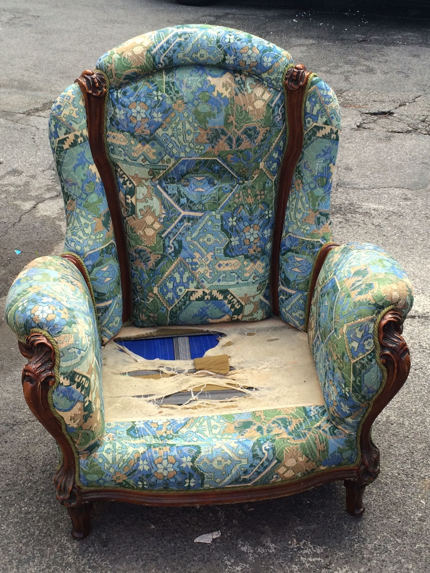 Representative photo of a worn antique armchair with torn floral upholstery, before restoration