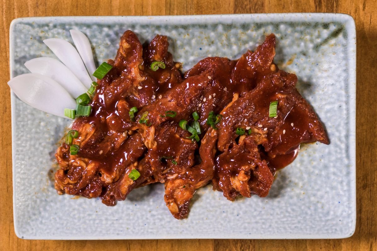 Representative photo: glazed adobo-marinated meat with green onion on a plate.