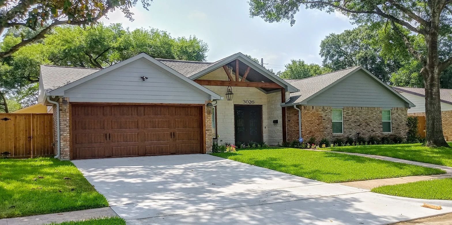 Remodeled Houston home exterior with new siding, brick and wood garage door by Olivo Remodeling