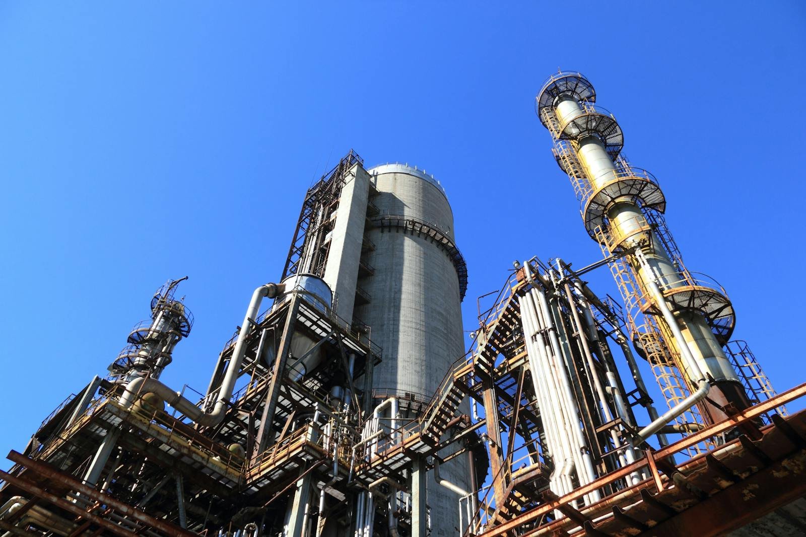 Industrial plant with tall process towers and stacks against the sky — typical of a pulp or chemical mill.