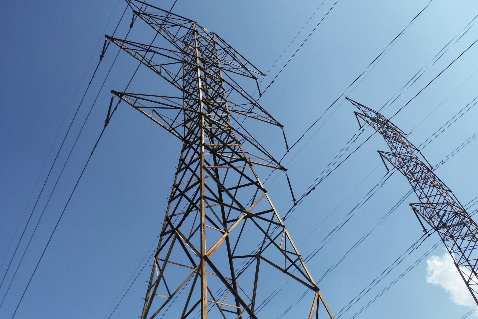 High-voltage transmission towers and overhead conductors stretching against the sky — context for plant power distribution scope.