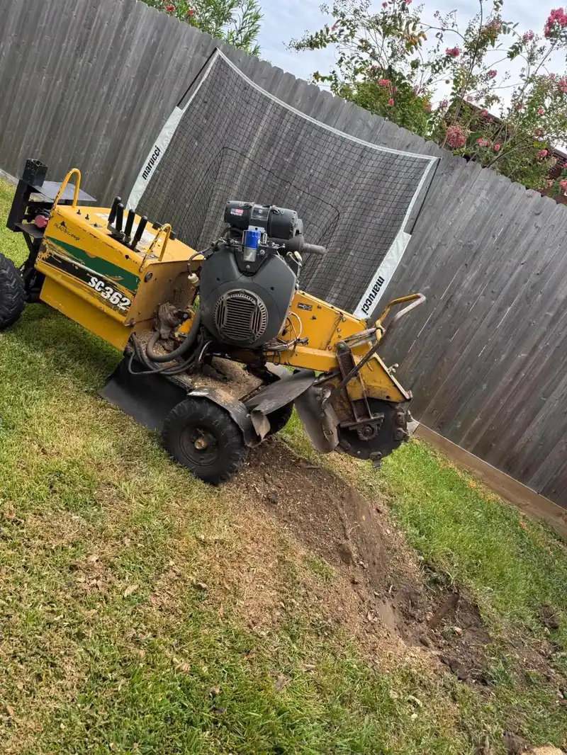 Second angle of the grinder working a stump in a narrow side yard next to a fence