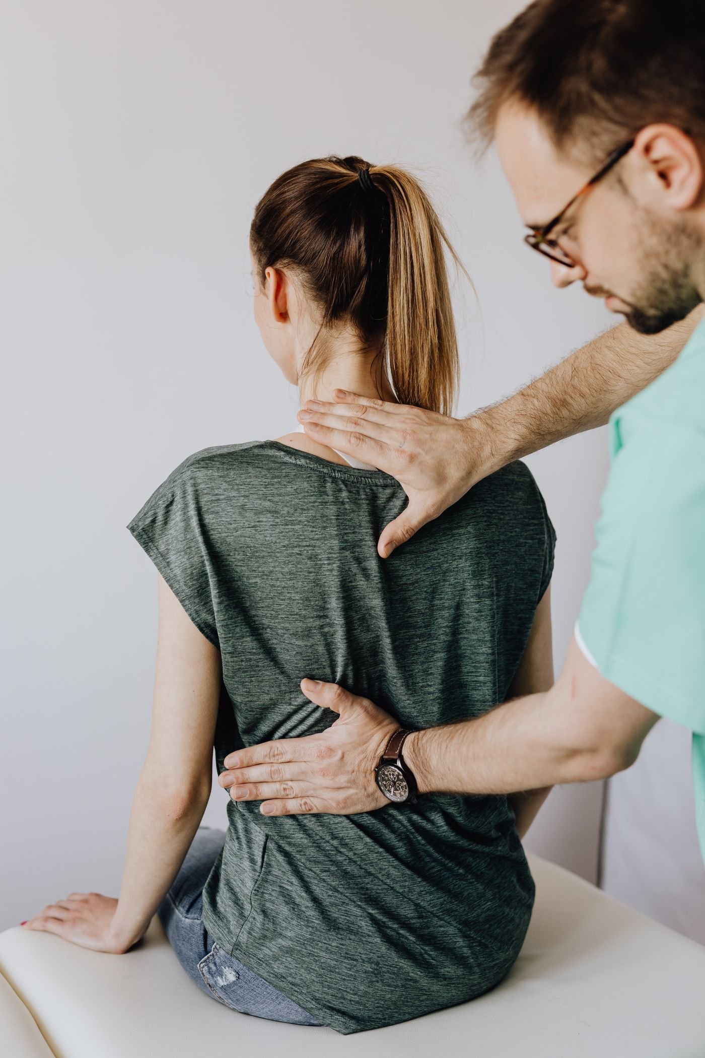 Representative photo of a chiropractor carefully assessing a patient's spine and posture in a calm clinic